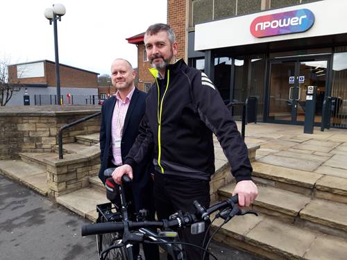 Two men with a bike outside npower office